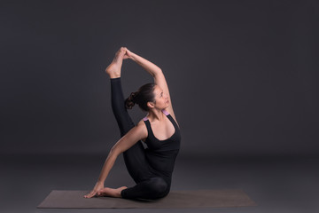 Young calm beautiful woman of the brunette with long hair wearing black sportswear. in yoga pose