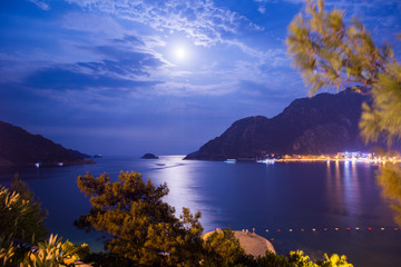 Evening view of the town of Icmeler. The bay is surrounded by mountains. Night life. Beach illuminated by evening lights