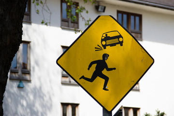 Yellow sign about a person running in front of a car