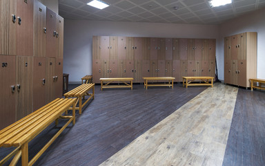 Large clean locker room interior. Beautiful and modern dressing room with benches in fitness gym