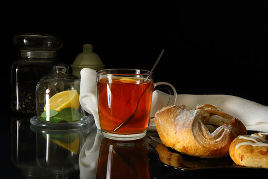 Mug of tea with lemon and sweet rolls
