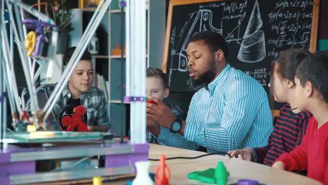 Excited school kids and teacher examining technology of three dimensional printing in laboratory. Static 4K shot on Red cinema camera.