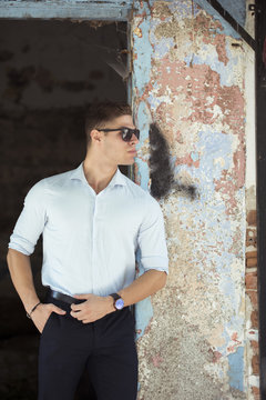 Fashion handsome young man lean on a pattern old wall wear shirt with cuffed sleeves