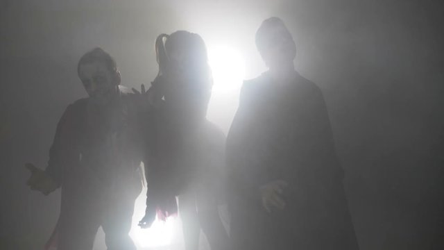 Horror zombie friends males and female dancing in foggy forest on halloween night in slow motion