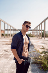 Good looking man wear unbuttoned shirt showing his great abs. Outdoor fashion and fitness shoot