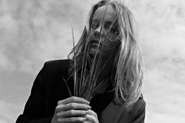 Art+Fashion photo of a young woman holding grass