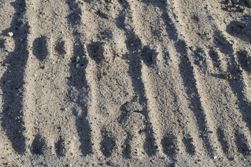 Traces from the car's tire. Relief in the sand. Imprints in the sand. Interesting background. Natural texture. Traces on a dirt road. Impressions of wheels on the ground.