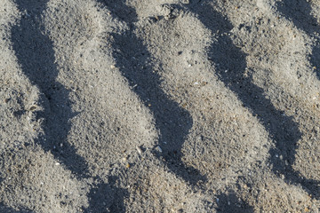 Traces from the car's tire. Relief in the sand. Imprints in the sand. Interesting background. Natural texture. Traces on a dirt road. Impressions of wheels on the ground.