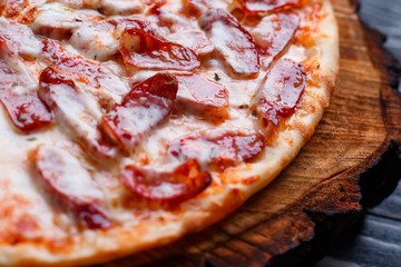 Delicious yummy fresh pizza with bacon, salami, ham and pepperoni and appetizing crust, close up. Italian food, pizzeria concept