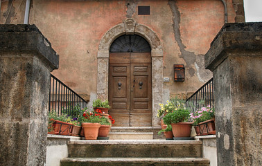 Fototapeta na wymiar old wooden door decorated with flowerpots from the medieval town, Italy