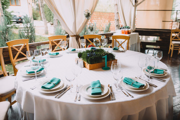 Banquet. Banquet table with a white tablecloth, decorated with fresh grass and small flowers in rustic style, as well as with turquoise napkins on the plates