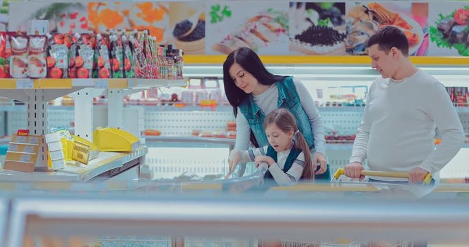 Family with child choosing food in the section of frozen products. Shopping in the hypermarket