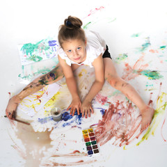 A little girl paints with paint and brush.