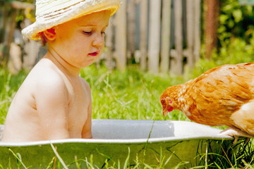 Rest in the countryside, summer holidays and child development in harmony with nature concept. Beautiful little child girl bathing outdoors and having fun with chickens.