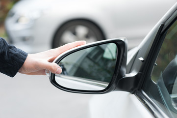 Young human hand is preparing or correct car mirror for the trip or travel from car window.