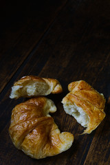 Freshly baked croissants in a black ceramic plate on the dark wooden background. Baking/pastry background. Concept for croissants making. Free space for text,two croissants on dark wood table