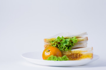 Simple breakfast in white plate, sandwich, oranges and fruit juice