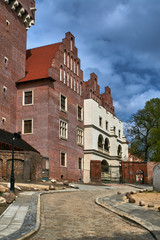 A cobbled street, a gate and a reconstructed royal castle in Poznań.