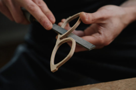 Close up of artisan hands filing a wooden eyeglasses frame with a file