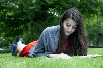 Young beautiful woman listening a book outdoors in old part of European city as symbol of knowledge and studies