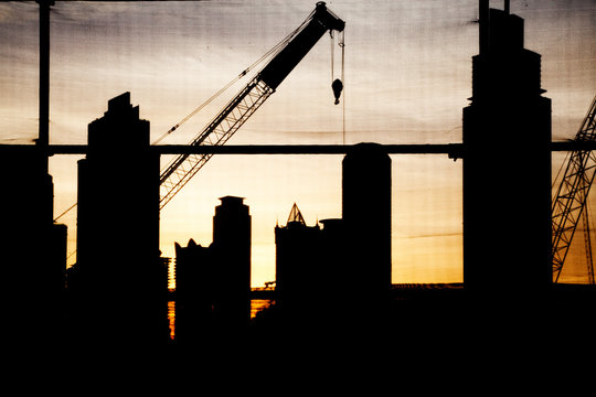 abstract photo of construction site with crane and skyscrapers in Dubai downtown at sunset - fast growing city concept