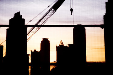 abstract photo of construction site with crane and skyscrapers in Dubai downtown at sunset - fast growing city concept