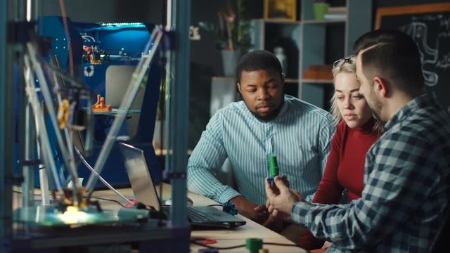 Group of multiracial scientists discussing process of contemporary 3d printing and future possibilities. Static 4K shot on Red cinema camera.