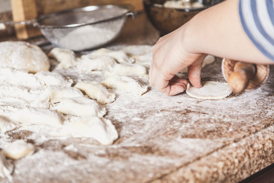 Female hands roll out dough with wooden rolling pin