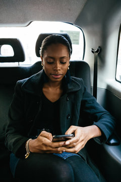 Woman travelling in a taxi using her mobile phone