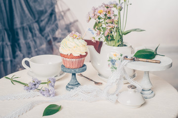 Cup cakes with cream cheese topping on beautiful wooden cake stand with flowers