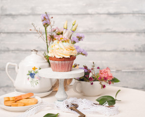 Cup cakes with cream cheese topping on beautiful wooden cake stand with flowers