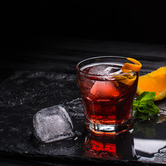 Mezcal Negroni cocktail. Italian aperitivo. Citrus peel. Ice.