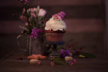 Cup cakes with cream cheese topping on beautiful wooden cake stand with flowers