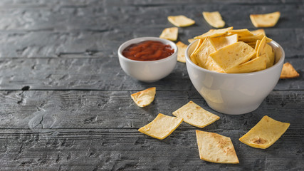 Chili sauce. Chips from a Mexican tortilla. The rustic table.