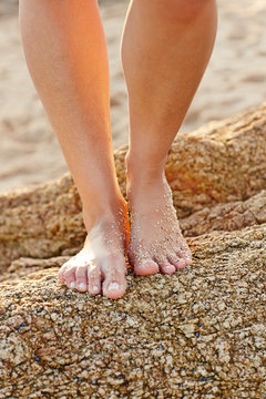 Woman's feet on rock on the beach on vacation in Mexico