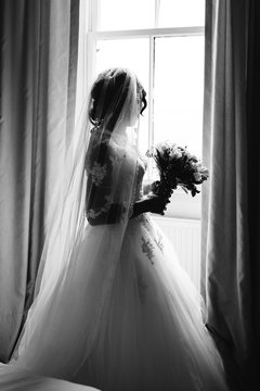 African bride holding flowers by a window.