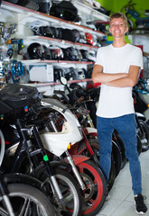 Portrait of cheerful male standing near the bike in the shop