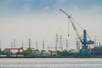 Power plant crane situated near the river with cloudy sky background