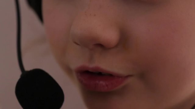 Closeup of a cute little girl in headphones singing in a microphone. slow motion