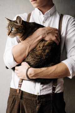 A Young Man Is Holding A Cat