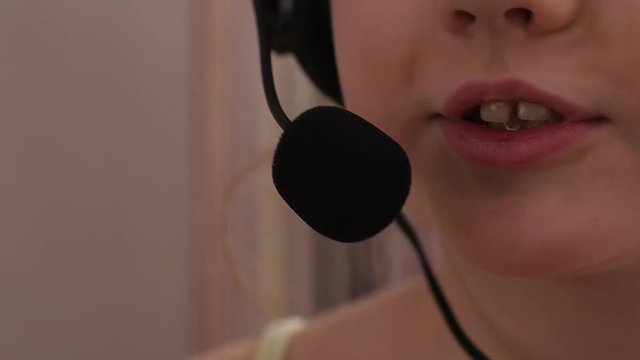 Closeup of a cute little girl in headphones singing in a microphone. slow motion
