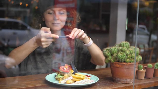 Woman Taking A Photo Of Food With Smartphone In Cafe