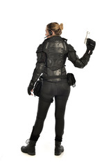 full length portrait of female  soldier wearing black  tactical armour, holding a gun, isolated on white studio background.