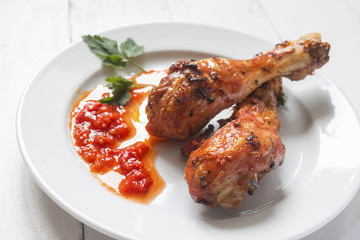 two appetizing baked sharp chicken legs with sauce on a plate