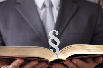 Judge Holding Law Book With Paragraph Symbol