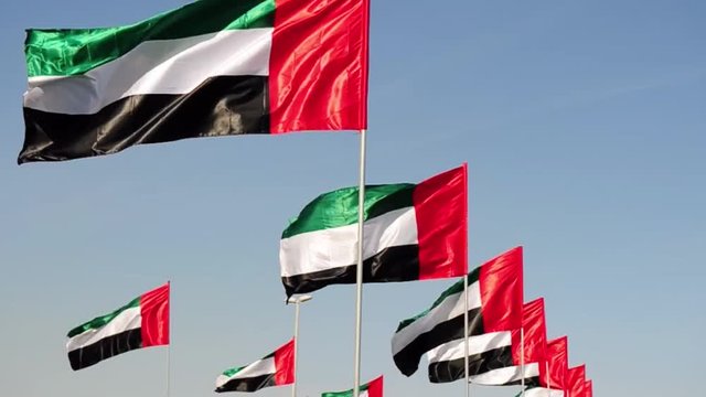 United Arab Emirates flags over blue sky.