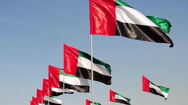 United Arab Emirates flags over blue sky.