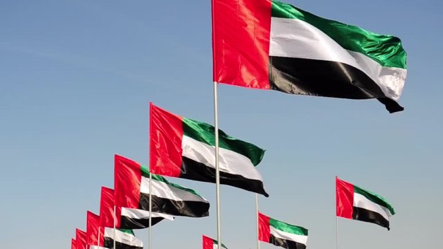 United Arab Emirates flags over blue sky.