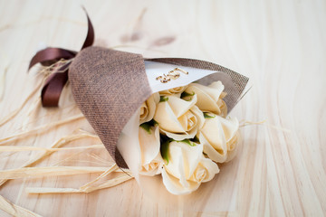 CREAM white roses flowers with valentine festival gift and beautiful blur bouquet and love word on the bouquet. flower on the wood background