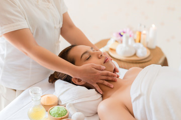 Obraz na płótnie Canvas Beautiful Asian girl relaxing receiving facial massage in a spa salon